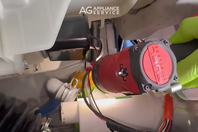 AG Appliance Service technician removing GE washer drain pump during repair