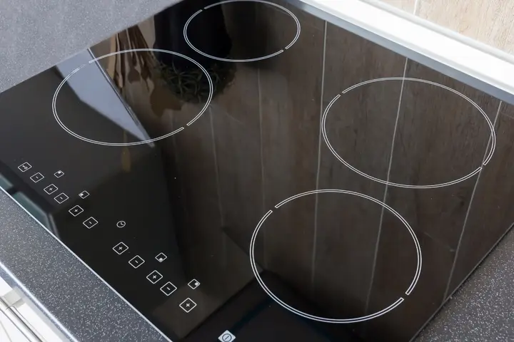 Black glass cooktop with four outlined cooking zones and touch controls along the edge