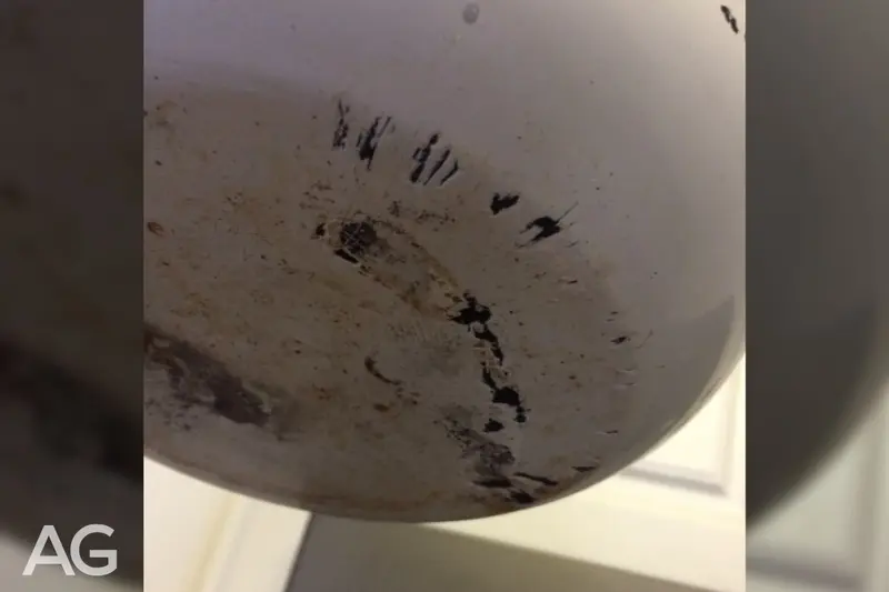 Grease and residue on an older pan that can damage a glass top range
