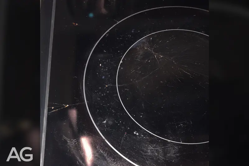 Spiderweb cracks in a glass cooktop caused by a dropped pan