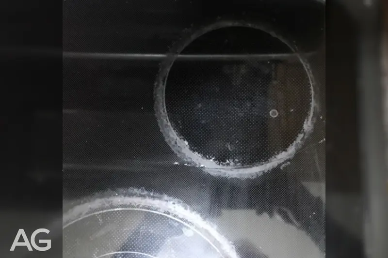 Starchy spill and residue left on a glass cooktop after an overflow
